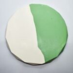 Round foam ball painted white on the left half and green on the right half. The surface appears faceted due to polygonal panels and the ball rests on a light background. - Bling On Decor® | Luxury Handmade Home Decor ANJU BALA