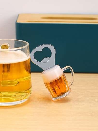Beer glass with frothy top and a small matching beer mug on a wooden table; a metal bottle opener with a heart-shaped cutout sits nearby, teal box in the background. - Bling On Decor® | Luxury Handmade Home Decor ANJU BALA