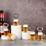 Row of beer mugs with foamy tops on white blocks, with heart-shaped bottle openers on top, and a Budweiser bottle on the left against a gray backdrop. - Bling On Decor® | Luxury Handmade Home Decor ANJU BALA