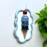 BLING-ON-Blue-Ice-Cream-Cone-3D-Wall-Art-Sculpture-Luxe-Pop-Art-Decor-Bling-On-3.webp - Bling On Decor® | Luxury Handmade Home Decor Decorative blue wavy frame surrounding a stacked ice cream cone with cherries on top and green plant on the side - Bling On Decor® | Luxury Handmade Home Decor ANJU BALA