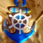 Plastic toy anchor with a white ship's wheel attached on top, blue and gold accents on a brown background, nautical plaything for children - Bling On Decor® | Luxury Handmade Home Decor ANJU BALA