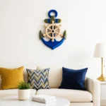 Nautical wall art featuring a blue anchor with a wooden ship wheel above a beige sofa, flanked by mustard and blue cushions. - Bling On Decor® | Luxury Handmade Home Decor ANJU BALA