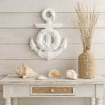 Coastal still life: a large white anchor wall decor above a white wooden table with seashells and a woven vase of dried grasses. - Bling On Decor® | Luxury Handmade Home Decor ANJU BALA