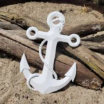 White decorative anchor with a rope wrapped around it, resting on sand with driftwood nearby. - Bling On Decor® | Luxury Handmade Home Decor ANJU BALA