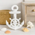 White nautical anchor decoration featuring a wheel in the center, placed with seashells near a wicker basket and light wooden table. - Bling On Decor® | Luxury Handmade Home Decor ANJU BALA