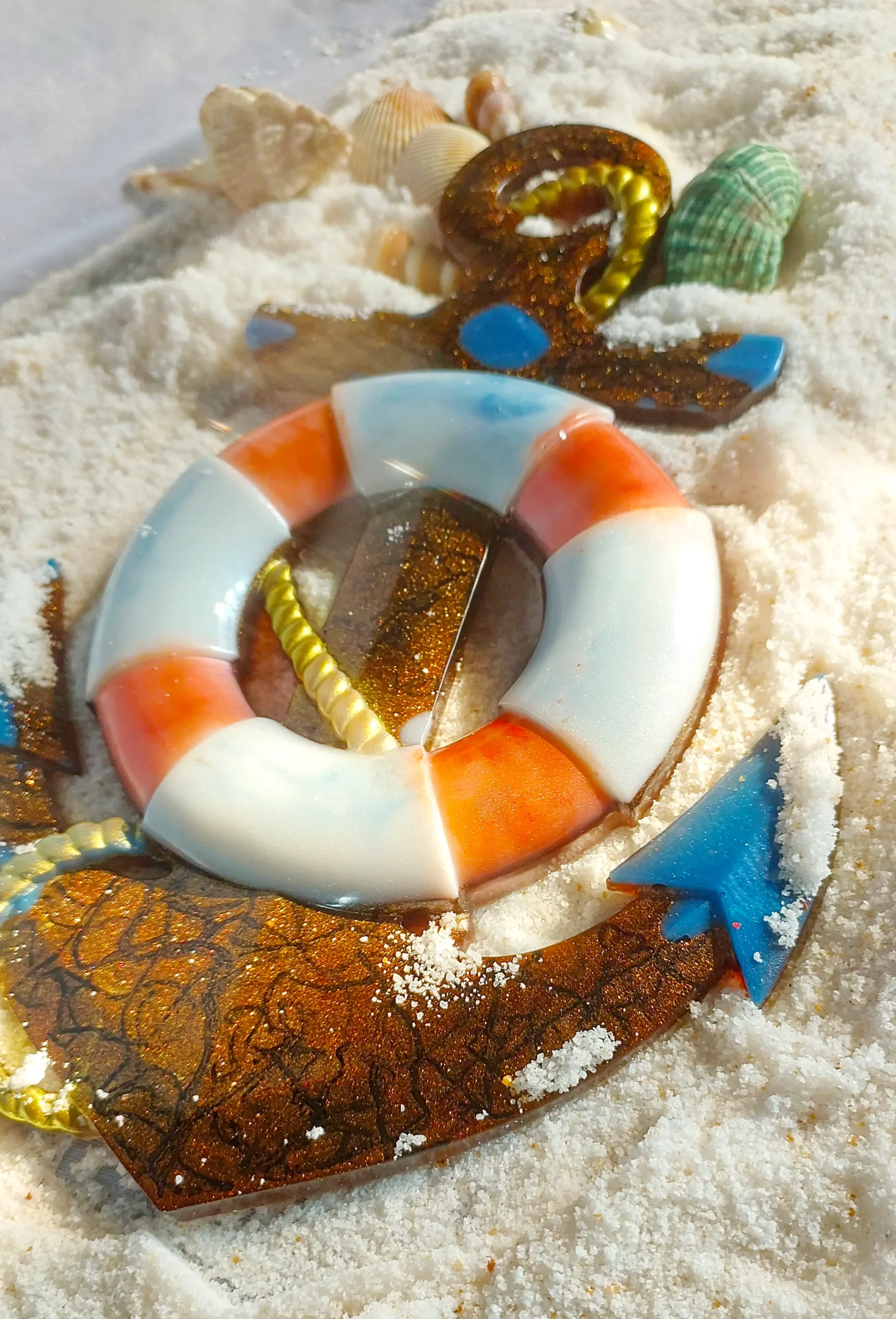 Colorful beach-themed ornament in white sand: an orange-and-white lifebuoy with shells and a glittery brown starfish piece. - Bling On Decor® | Luxury Handmade Home Decor ANJU BALA