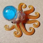 Glittery orange octopus toy with a blue dome head on a flat surface. - Bling On Decor® | Luxury Handmade Home Decor ANJU BALA