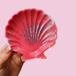 Hand holding a pink scallop-shell decorative dish with glitter against a pink background. - Bling On Decor® | Luxury Handmade Home Decor ANJU BALA