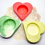 Bling-On-Tealight-Candle-Holder-I-set-of-3-Valentines-Day-Gift-Minimalistic-Home-decor-Handmade-Gifts-8-1.webp - Bling On Decor® | Luxury Handmade Home Decor Red heart-shaped object with layered cutouts centered on a decorative beige and white patterned background, surrounded by green and yellow hearts. - Bling On Decor® | Luxury Handmade Home Decor ANJU BALA