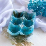 Blue wave-shaped ceramic tray with leaf patterns, set against white fabric and a blue hydrangea bouquet in the background. - Bling On Decor® | Luxury Handmade Home Decor ANJU BALA