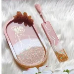 Decorative pink handheld mirror with abstract white line art, a glittery gold base, and a matching pink bookmark with a tassel, set on a white fluffy surface. - Bling On Decor® | Luxury Handmade Home Decor ANJU BALA