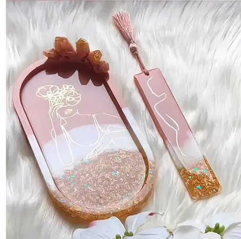 Decorative pink handheld mirror with abstract white line art, a glittery gold base, and a matching pink bookmark with a tassel, set on a white fluffy surface. - Bling On Decor® | Luxury Handmade Home Decor ANJU BALA