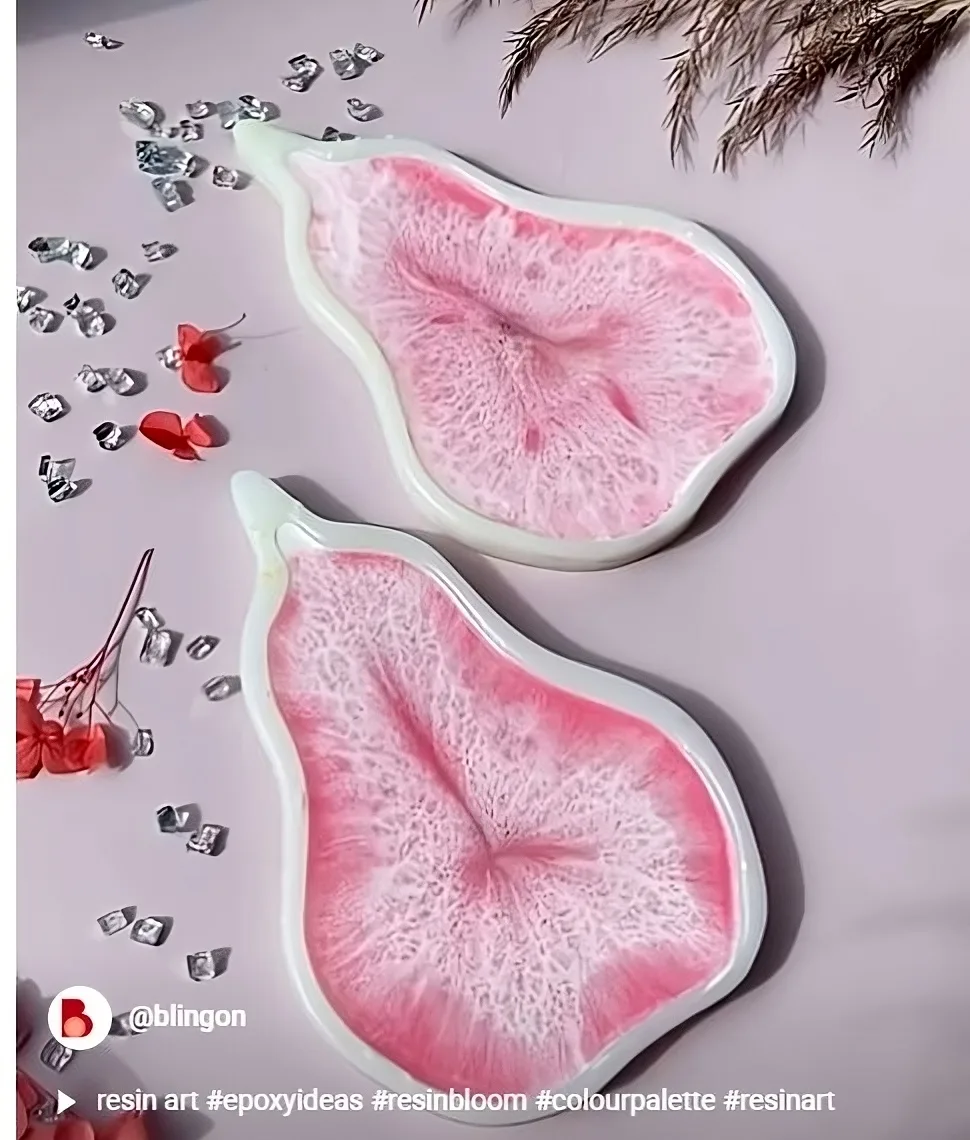 Two pink resin art pieces shaped like abstract leaves on a pale pink surface, accented with crystals and red flowers. - Bling On Decor® | Luxury Handmade Home Decor ANJU BALA