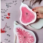 Two pink, flower-shaped silicone pads with textured centers on a light surface, with a hand holding one pad. - Bling On Decor® | Luxury Handmade Home Decor ANJU BALA