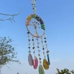 Hanging dreamcatcher with colorful beads and dangling gemstone pendants against a blue sky. - Bling On Decor® | Luxury Handmade Home Decor ANJU BALA