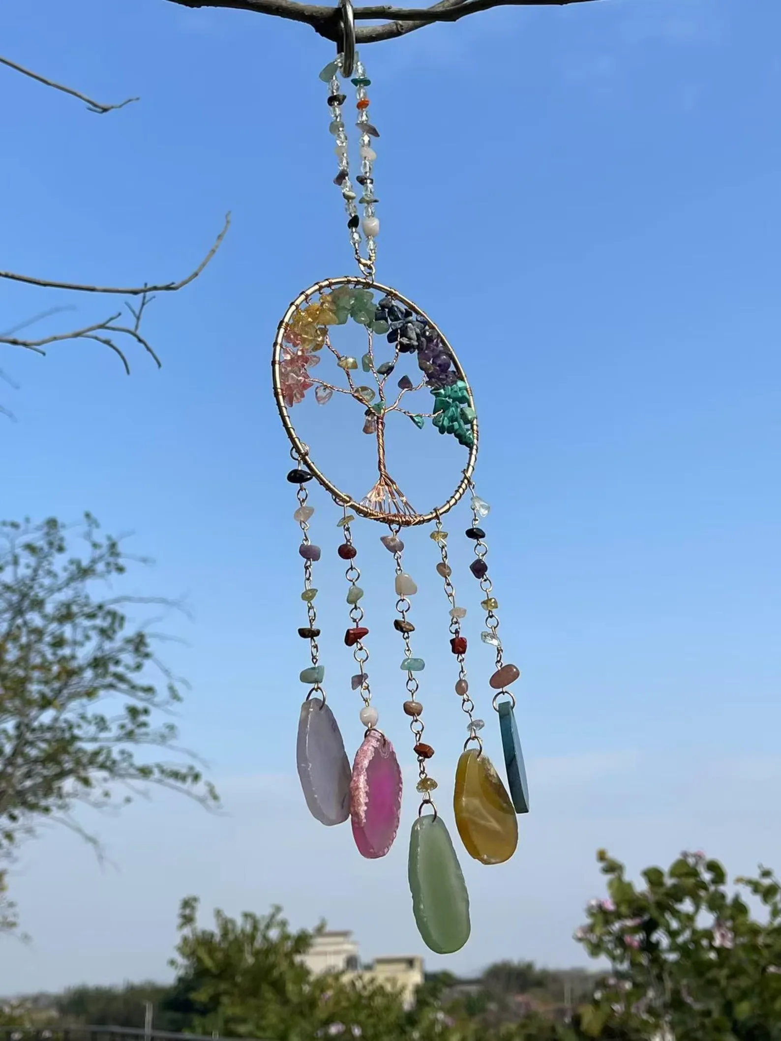 Hanging dreamcatcher with colorful beads and dangling gemstone pendants against a blue sky. - Bling On Decor® | Luxury Handmade Home Decor ANJU BALA