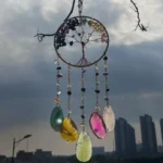 Dreamcatcher hanging in front of a city skyline with colorful bead charms and shells against a cloudy sky. (Informative) - Bling On Decor® | Luxury Handmade Home Decor ANJU BALA