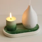 Lit candle beside a white teardrop-shaped essential oil diffuser on a white tray with a green base mat, creating a calming spa-like scene. - Bling On Decor® | Luxury Handmade Home Decor ANJU BALA