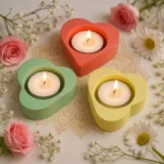 Illuminate-Your-Home-Tealight-Candle-Holder-Set-of-3-Valentines-Day-Gift-Minimalistic-Home-decor-Handmade-Gifts-1.webp - Bling On Decor® | Luxury Handmade Home Decor Three pastel heart-shaped tealight holders with lit candles, surrounded by pink roses and white daisies on a lace tablecloth. - Bling On Decor® | Luxury Handmade Home Decor ANJU BALA