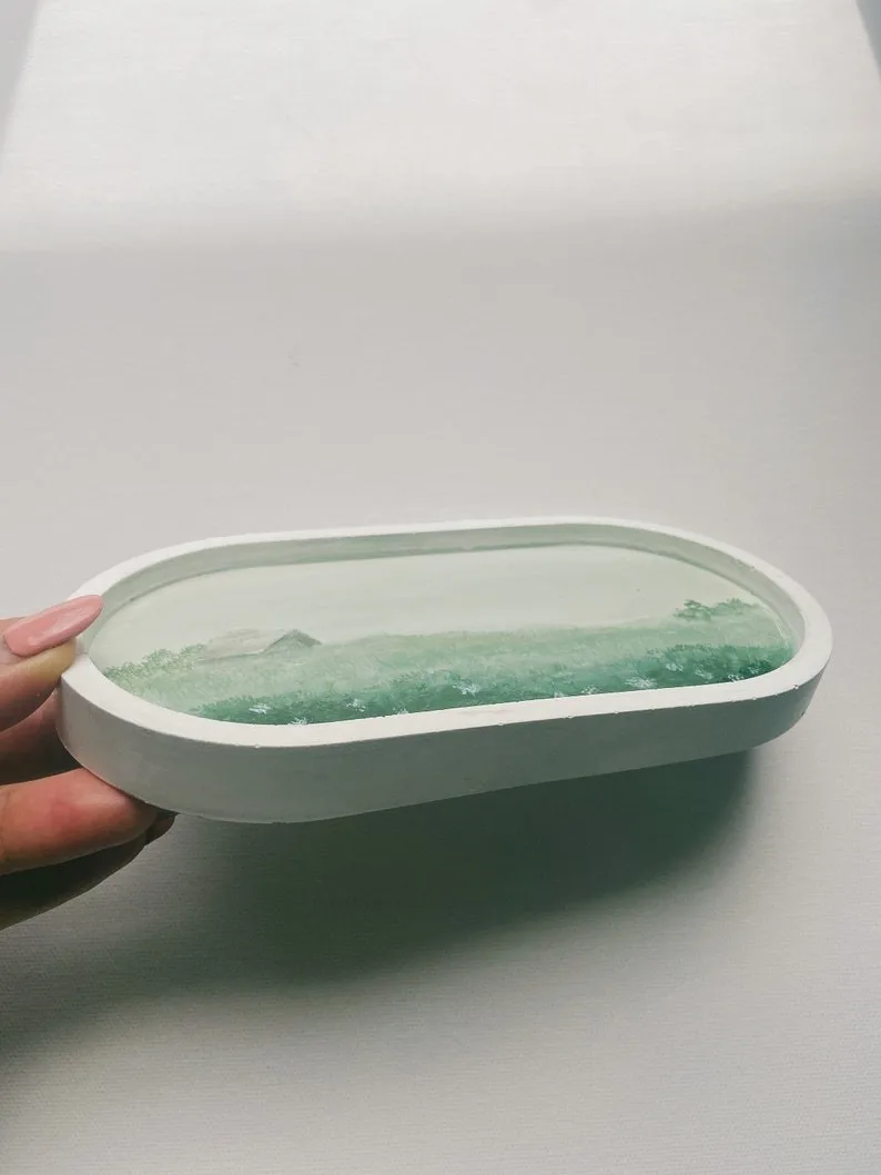 White oval dish held by a hand, containing a translucent green gel-like substance or soap slab embedded inside. - Bling On Decor® | Luxury Handmade Home Decor ANJU BALA