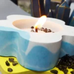 Blue and white heart-shaped birthday cake with a small flame candle and chocolate rocks on a yellow cake board. - Bling On Decor® | Luxury Handmade Home Decor ANJU BALA