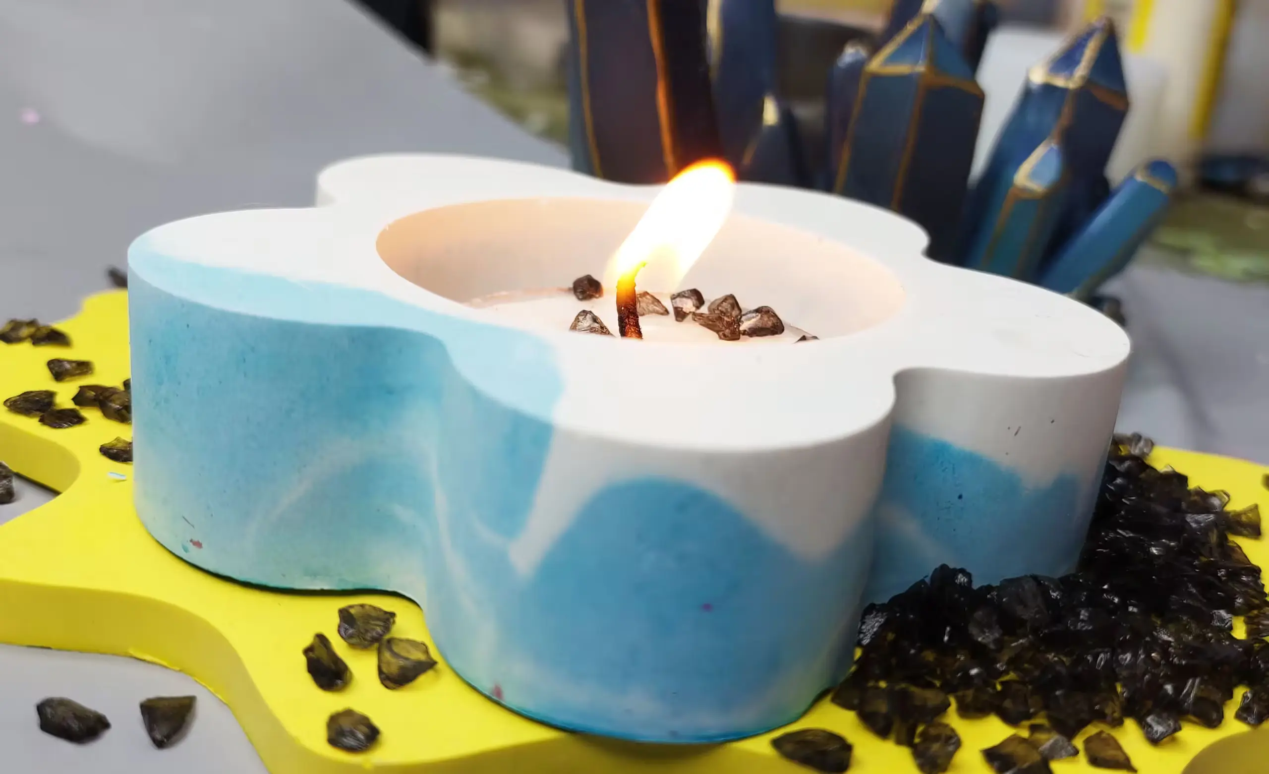 Blue and white heart-shaped birthday cake with a small flame candle and chocolate rocks on a yellow cake board. - Bling On Decor® | Luxury Handmade Home Decor ANJU BALA