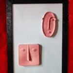 Modern-Abstract-3D-Face-Wall-Art-Frame-Handmade-Resin-Sculpture-Minimalist-Luxury-Home-Decor-by-Bling-On®-India-🇮🇳-5-scaled-1.webp - Bling On Decor® | Luxury Handmade Home Decor Pink clay sculptures of faces mounted on a white background inside a black frame, set on red fuzzy fabric. - Bling On Decor® | Luxury Handmade Home Decor ANJU BALA