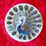 Decorative ceramic plate with a colorful peacock design on a red plush background. - Bling On Decor® | Luxury Handmade Home Decor ANJU BALA