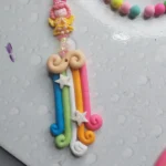 Pastel candy-inspired beaded necklace with a pink girl pendant and star charms on a pale dotted background. - Bling On Decor® | Luxury Handmade Home Decor ANJU BALA