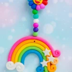 Polymer-Clay-Rainbow-Cloud-Window-Hanger-Handmade-Magic-for-Every-Space-✨-4.webp - Bling On Decor® | Luxury Handmade Home Decor Colorful rainbow keychain with a smiling sun flower at the top, beaded pink, blue, and green strand, and white stars against a pastel background. - Bling On Decor® | Luxury Handmade Home Decor ANJU BALA