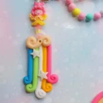 Colorful clay keychain with rainbow strands, stars, and a pink fairy figure on top; hangs from a pastel beaded chain. - Bling On Decor® | Luxury Handmade Home Decor ANJU BALA