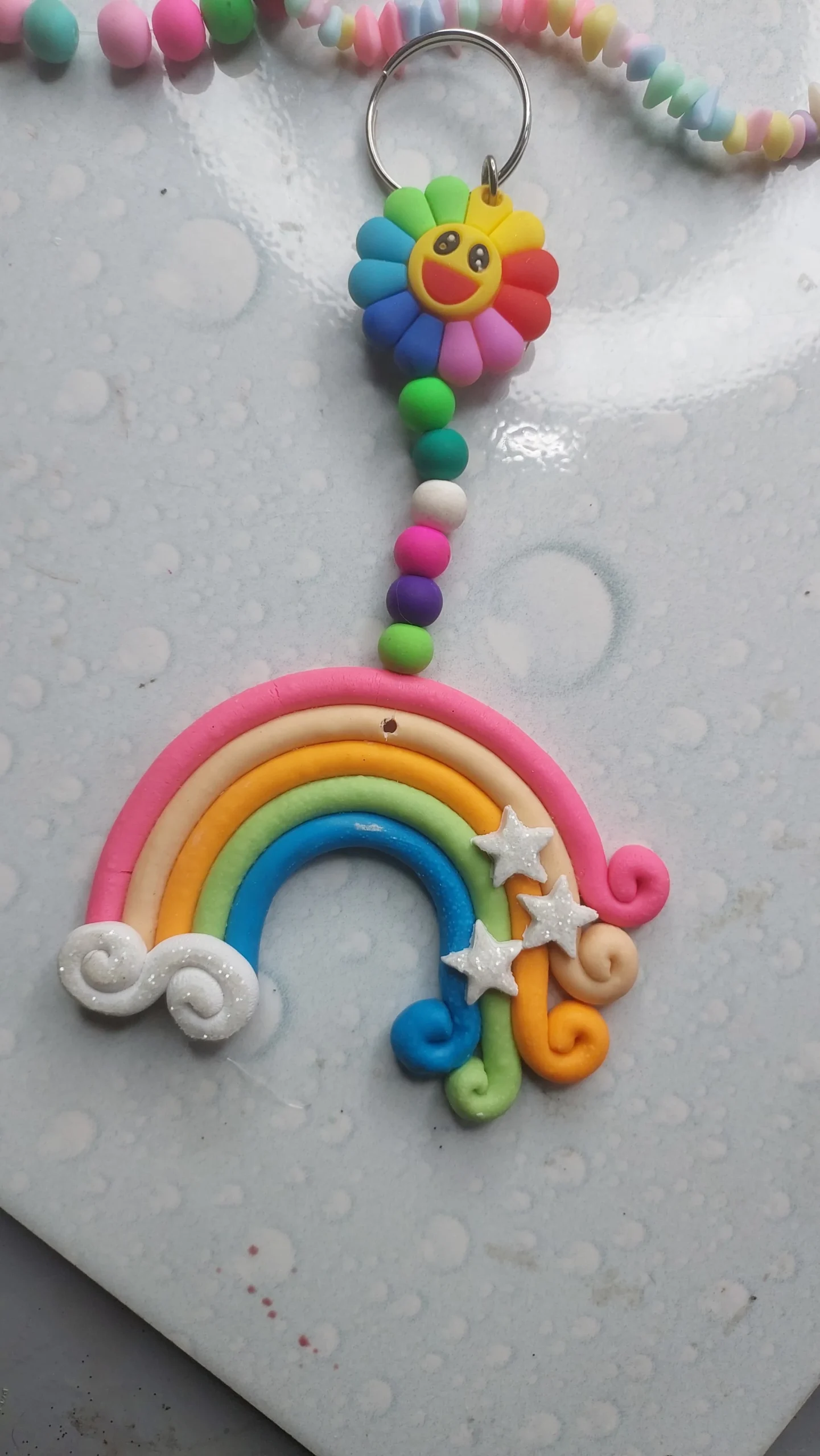 Polymer-Clay-Rainbow-Cloud-Window-Hanger-Handmade-Magic-for-Every-Space-✨-6-scaled-1.webp - Bling On Decor® | Luxury Handmade Home Decor Colorful rainbow clay keychain with a smiling sun face and a beaded tassel hanging from a keyring. - Bling On Decor® | Luxury Handmade Home Decor ANJU BALA