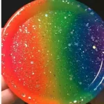 Round rainbow-colored disc with a glittery speckled surface, showing red to violet gradient across the circle.