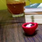 Resin-Love-Cup-table-Top-Desktop-Item-1.webp - Bling On Decor® | Luxury Handmade Home Decor Close-up of a jar of jam beside a stack of papers/notebooks on a wooden surface, with a red cup in the foreground. - Bling On Decor® | Luxury Handmade Home Decor ANJU BALA