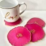White ceramic mug with a gold rim and the word 'love' in gold, resting on pink, flower-shaped coasters with gold edges. - Bling On Decor® | Luxury Handmade Home Decor ANJU BALA