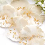 Ivory scallop shells arranged on a white marble surface with gold leaf accents and white flowers in the background. - Bling On Decor® | Luxury Handmade Home Decor ANJU BALA