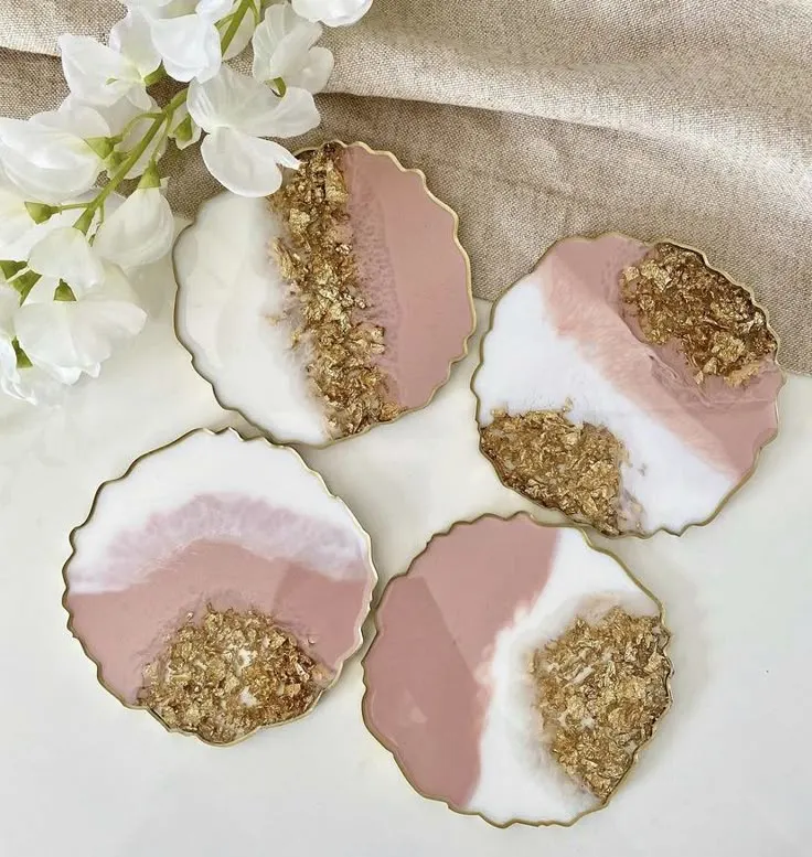 Resin-Pink-Floral-Coaster-Luxury-Handmade-Magic-for-Special-Moments-6-1.webp - Bling On Decor® | Luxury Handmade Home Decor Set of four scalloped-edged coasters featuring pink, white, and gold leaf geode designs on a light surface with white flowers nearby. - Bling On Decor® | Luxury Handmade Home Decor ANJU BALA