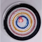 Close-up of a round, clear surface with concentric glitter rings in black, red, gold, blue, and pink, resembling a decorative target. - Bling On Decor® | Luxury Handmade Home Decor ANJU BALA