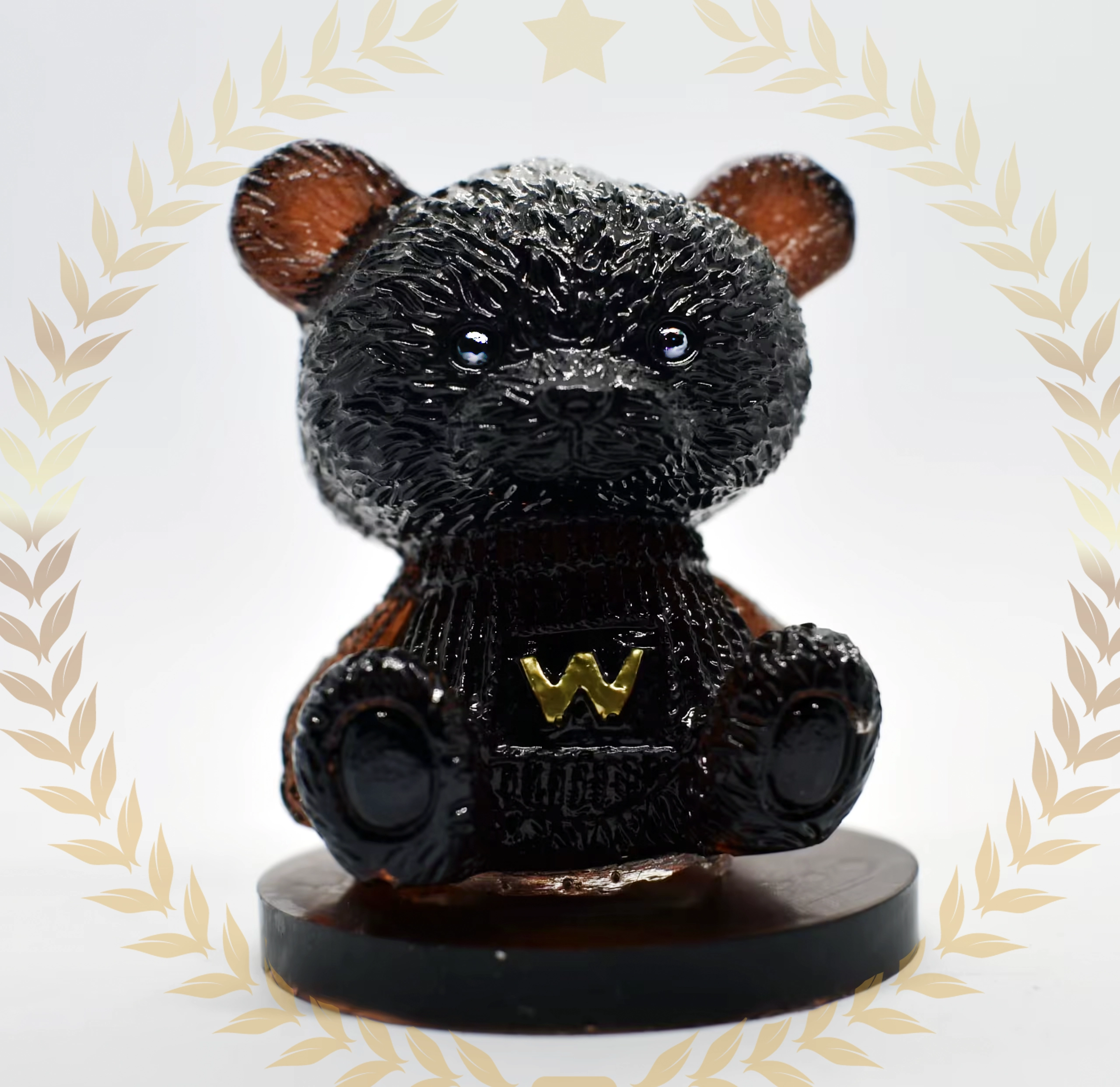 Glossy black bear figurine with a gold 'W' emblem on its chest, on a wooden pedestal, framed by a pale laurel border. - Bling On Decor® | Luxury Handmade Home Decor ANJU BALA
