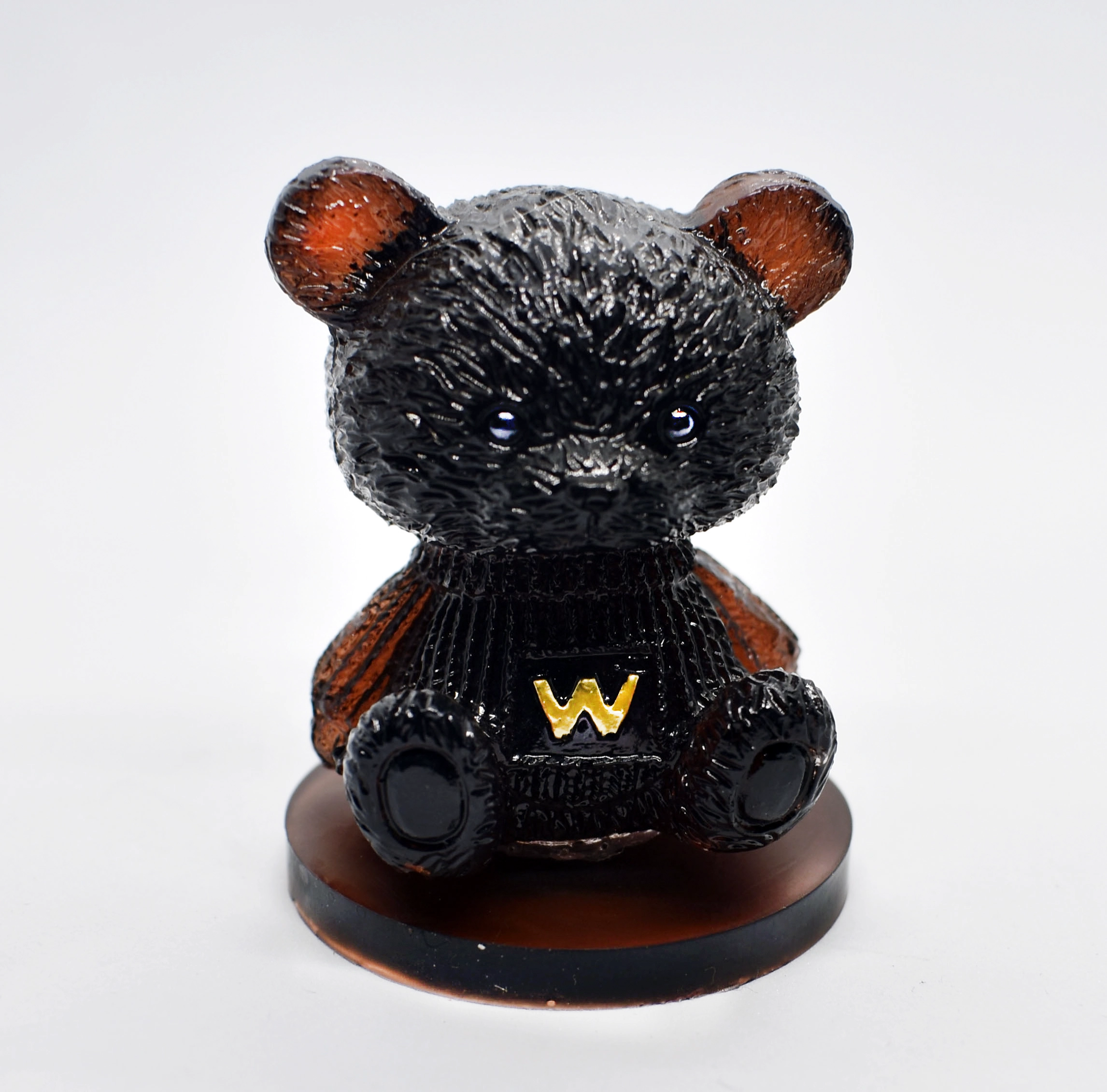 Close-up of a glossy black bear figurine with red inner ears and a yellow W on its chest, standing on a brown base. - Bling On Decor® | Luxury Handmade Home Decor ANJU BALA