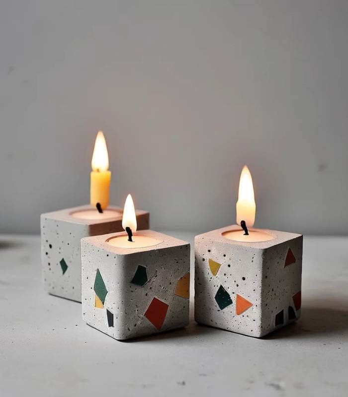 Three square terrazzo candles with colorful geometric flecks, lit and burning on a light gray surface. - Bling On Decor® | Luxury Handmade Home Decor ANJU BALA