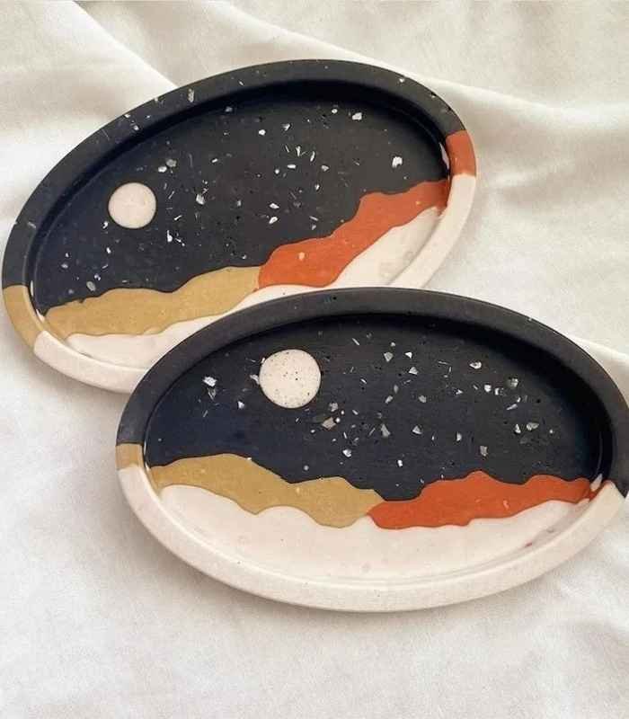 Two oval decorative trays with a night-sky design: dark background, white moon, and layered gold, beige, orange, and white waves. - Bling On Decor® | Luxury Handmade Home Decor ANJU BALA