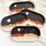 Four oval ceramic coasters with abstract desert dunes in black, orange, beige, and white. - Bling On Decor® | Luxury Handmade Home Decor ANJU BALA