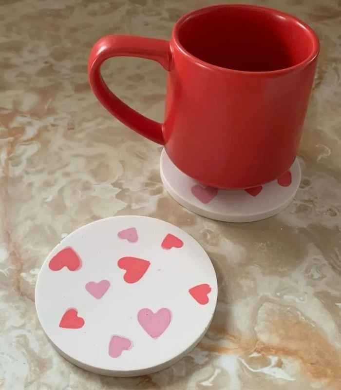 Red ceramic mug resting on a white heart-decorated coaster on a marble table, with a matching lid nearby. - Bling On Decor® | Luxury Handmade Home Decor ANJU BALA
