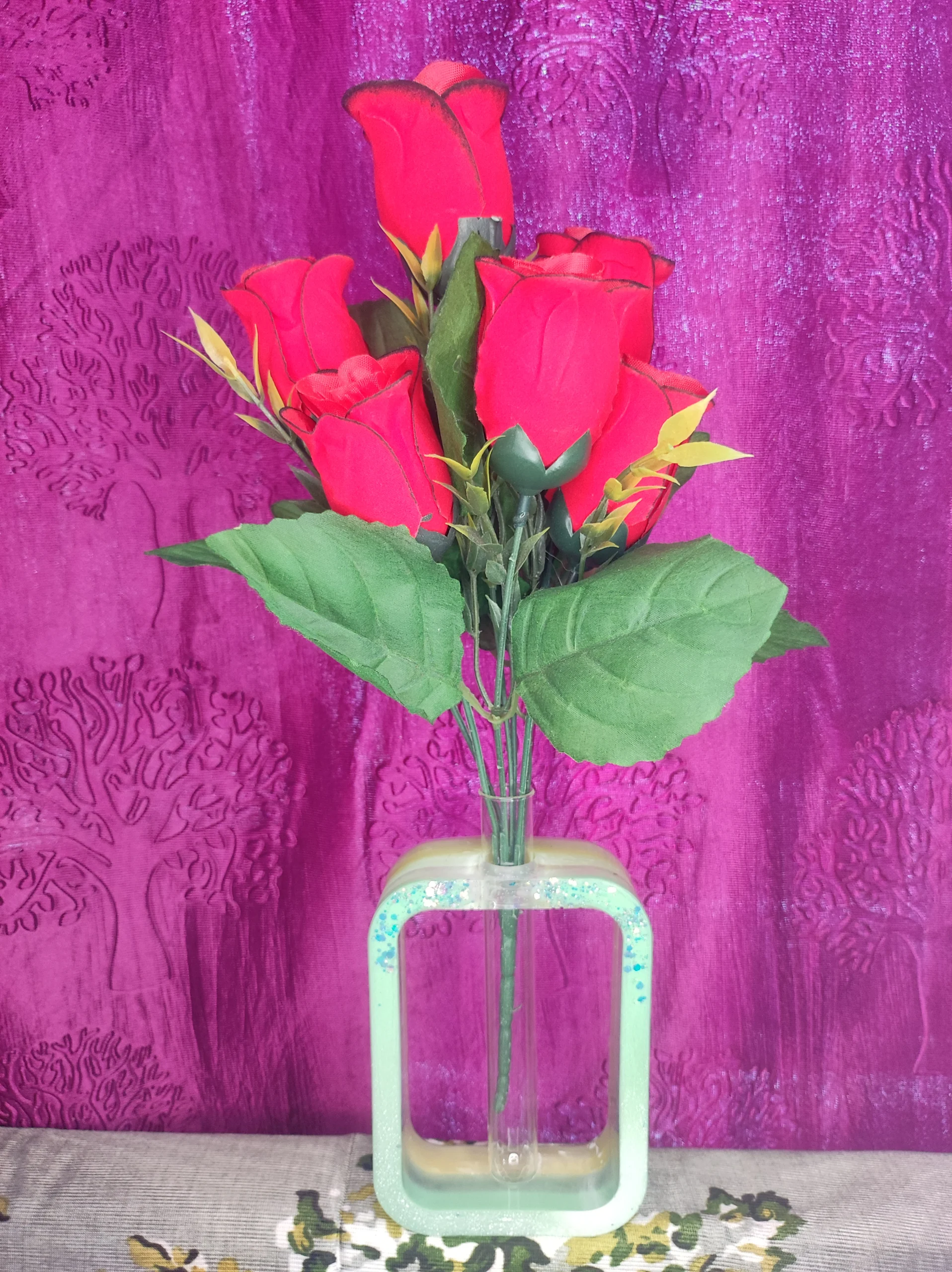 Bouquet of red roses in a glass vase nestled in a mint-green stand against a purple textured backdrop - Bling On Decor® | Luxury Handmade Home Decor ANJU BALA