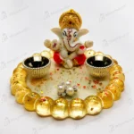 Bling-on®-handmade-lord-ganesha-resin-diya-holder-luxury-pooja-decor-decorative-oil-lamp-s-5-1webp - Bling On Decor® | Luxury Handmade Home Decor Small white Ganesha figurine with a gold crown sits at the center of a circular ring made of gold beads on a glittery base. Two decorative bowls flank the statue, and scattered confetti and pearl earrings lie in front. - Bling On Decor® | Luxury Handmade Home Decor ANJU BALA
